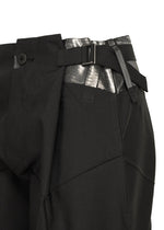 Close-up of the F-BT black tailored recycled polyester pants by 132 5. ISSEY MIYAKE, featuring a silver metallic waistband detail, foil processing, side buckle, and black button closure against a white background.