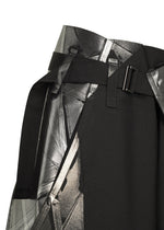Close-up of the F-BT black skirt by 132 5. ISSEY MIYAKE, featuring a wide belt with a rectangular metal buckle, abstract silver and gray geometric print, and subtle foil detailing for shine.