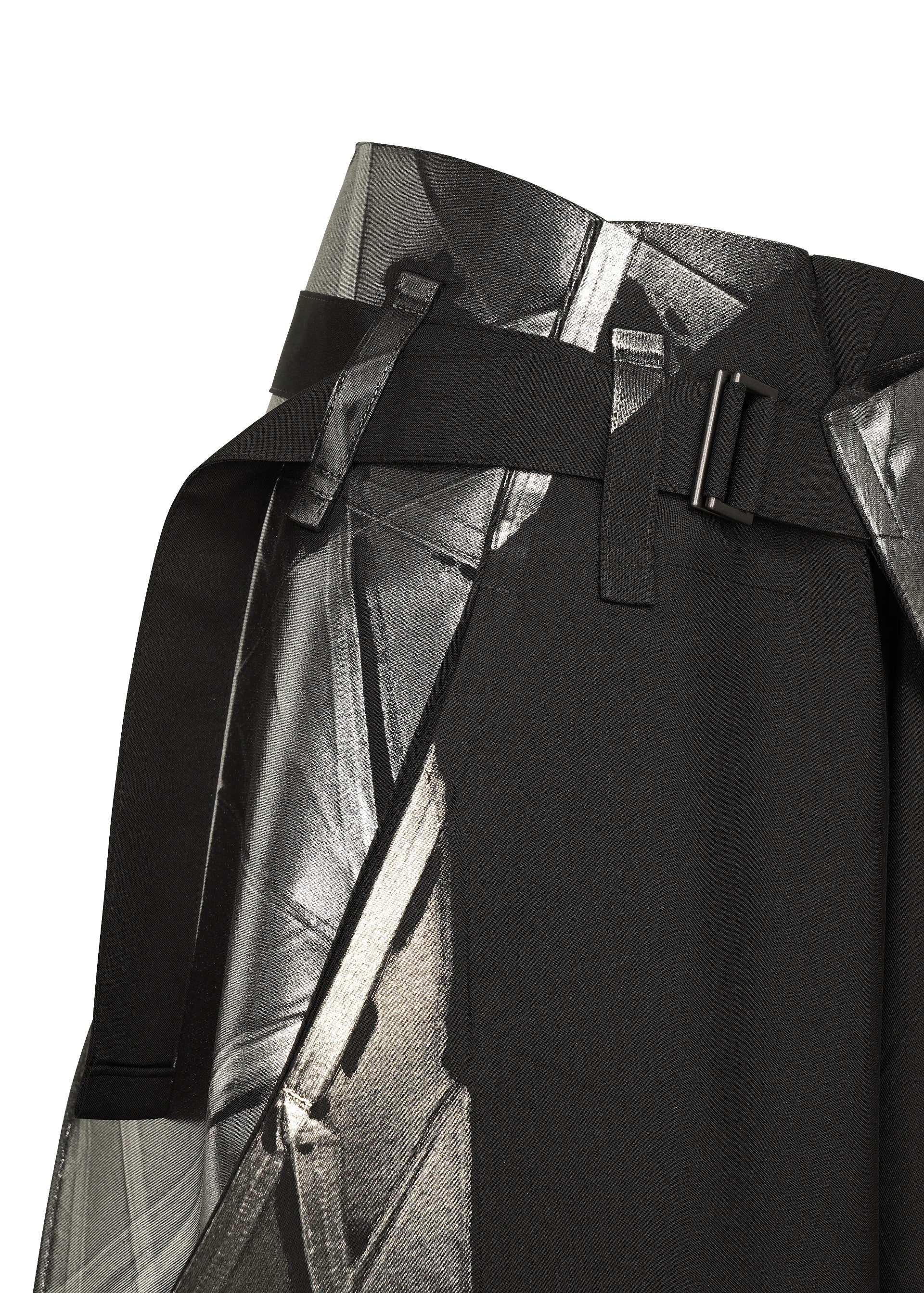 Zoomed view Close-up of the F-BT black skirt by 132 5. ISSEY MIYAKE, featuring a wide belt with a rectangular metal buckle, abstract silver and gray geometric print, and subtle foil detailing for shine.