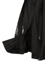 A close-up of the No.3-1 by 132 5. ISSEY MIYAKE, featuring a black pleated skirt with button detailing, sheer triangular cut-outs at the hem, layered fabric, and hints of a convertible skirt-pants design.