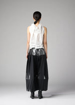 A person faces away, wearing 132 5. ISSEY MIYAKE's No.10-1: a sleeveless white foil-detail ruffled top with metallic silver waistband, wide black pleated mesh-panel pants, black ankle boots, and sleek dark hair tied back.