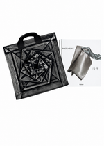 A black geometric tote bag with layered square motifs is showcased beside the ISSEY MIYAKE (Limited Collectors Edition) book by ISSEY MIYAKE BOOKS, whose cover features a metallic, sculptural bag—an eye-catching tribute to Issey Miyake’s avant-garde design philosophy.