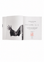 An open book from ISSEY MIYAKE (Limited Collectors Edition) by ISSEY MIYAKE BOOKS displays a black-and-white photo of a person in a flowing garment on the left and stylized text with a red stamp on the right, embodying the design philosophy that characterizes this collector’s edition.
