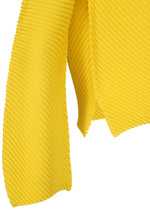 A close-up of ISSEY MIYAKE’s SHIFTED MISTY PLEATS: textured yellow fabric with diagonal ribbing, artfully draped to highlight its folds and thickness—ideal for a unique design or a stylish pleated top.