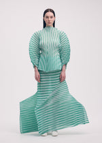 A woman faces forward in ISSEY MIYAKE's GENERIC STRIPES (HAND PLEATS) set: a striped pleated top with voluminous sleeves and matching flowing skirt. She has straight dark hair, white shoes, and stands against a plain white background.