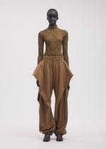 Wearing the CHIFFON TWIST 3 by ISSEY MIYAKE, a person poses in a fitted brown recycled polyester turtleneck top and high-waisted wide-leg pants with sculptural side panels against a plain light background.