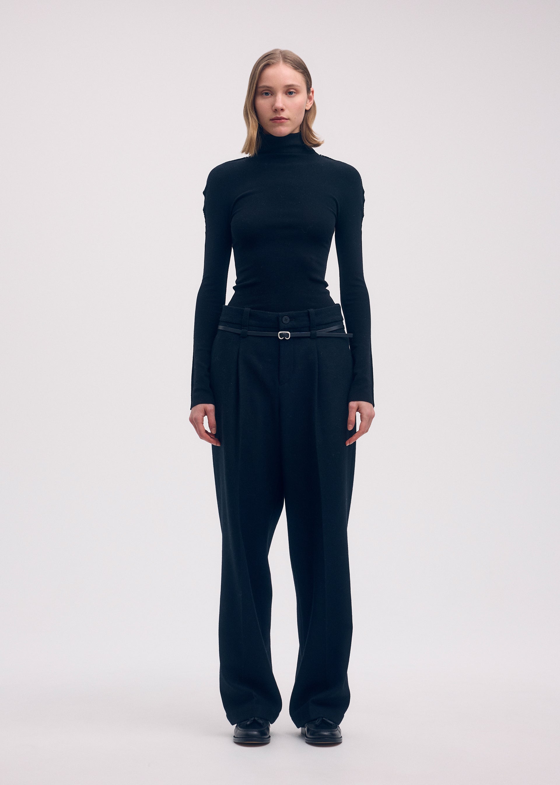 Zoomed view A person stands facing forward against a plain background, carrying the ISSEY MIYAKE COTTON BAGUETTE BK-58. Their arms rest by their sides and their expression is neutral.