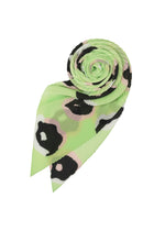 The ISSEY MIYAKE VERVE PLEATS STOLE, in mint-green with black, white, and pale pink abstract hand-drawn spots, is shown rolled up to reveal its pointed ends against a white background. - GREEN-HUED （no.66）