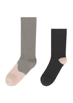 Two crew-length socks—one gray with light pink toe and heel, the other black with light pink accents—pair perfectly with ISSEY MIYAKE’s KARST FINCH sneakers or any colorful footwear.