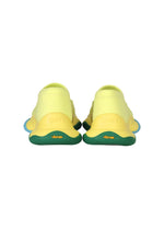 The ISSEY MIYAKE KARST FINCH sneakers feature a yellow upper, green sole, and blue accents, viewed from the back. The brands ISSEY MIYAKE and KARST FINCH appear on the heel and sole, emphasizing their unique, colorful design.