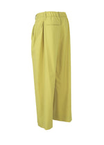 The ISSEY MIYAKE BELTED WOOL PANTS are wide-leg yellow trousers in a washable wool blend Saxony fabric with an elastic waistband, side pockets, and one back pocket, shown on a white background.