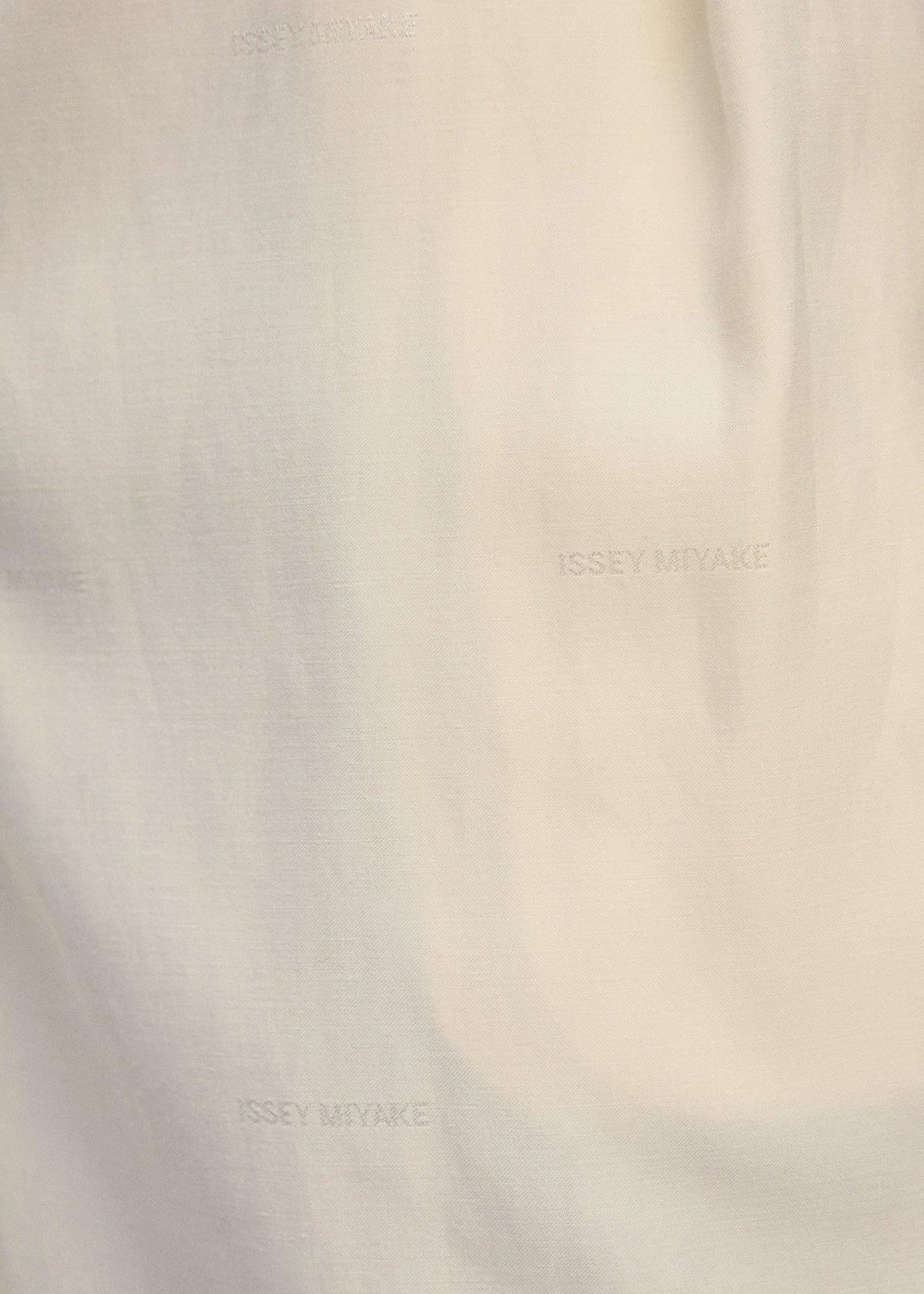 A close-up of off-white PALINDROME fabric by ISSEY MIYAKE, featuring the brand name subtly repeated in a darker shade for a textured, minimalist pattern. view 15 of 15