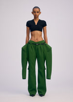 A person with short hair models ISSEY MIYAKE's ARMS: a fitted black crop top paired with oversized, triple-woven wide-leg pants featuring draped extra fabric, all against a plain light background.