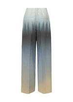 Back view of ISSEY MIYAKE PLUMAGE pants: high-waisted artisan design with hand-painted wide pattern and a five-color gradient shifting from light beige at the hem to deep gray near the waistband.