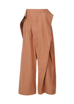 The FLUTTERING PANTS by ISSEY MIYAKE are high-waisted, wide-leg tan culottes featuring an asymmetric overlapping front panel and loose fit, made from high-density double-woven fabric for structure and a subtle matte finish.