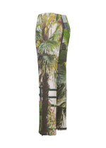The ISSEY MIYAKE URBAN JUNGLE PLEATS is a pleated, ankle-length skirt with a fitted waist and straight silhouette, featuring a vibrant city-inspired palm tree and foliage print in green, yellow, and brown.