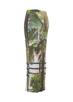 The ISSEY MIYAKE URBAN JUNGLE PLEATS is a mid-length, fitted skirt with vertical ribbing and a bold jungle palm print on a light base, shown from the side on a white background.