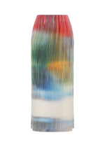 The OBSCURE PLEATS midi skirt by ISSEY MIYAKE is a high-waisted, pleated polyester design featuring a red, green, yellow, blue, and white gradient pattern on a white background, showcased against a plain white backdrop.