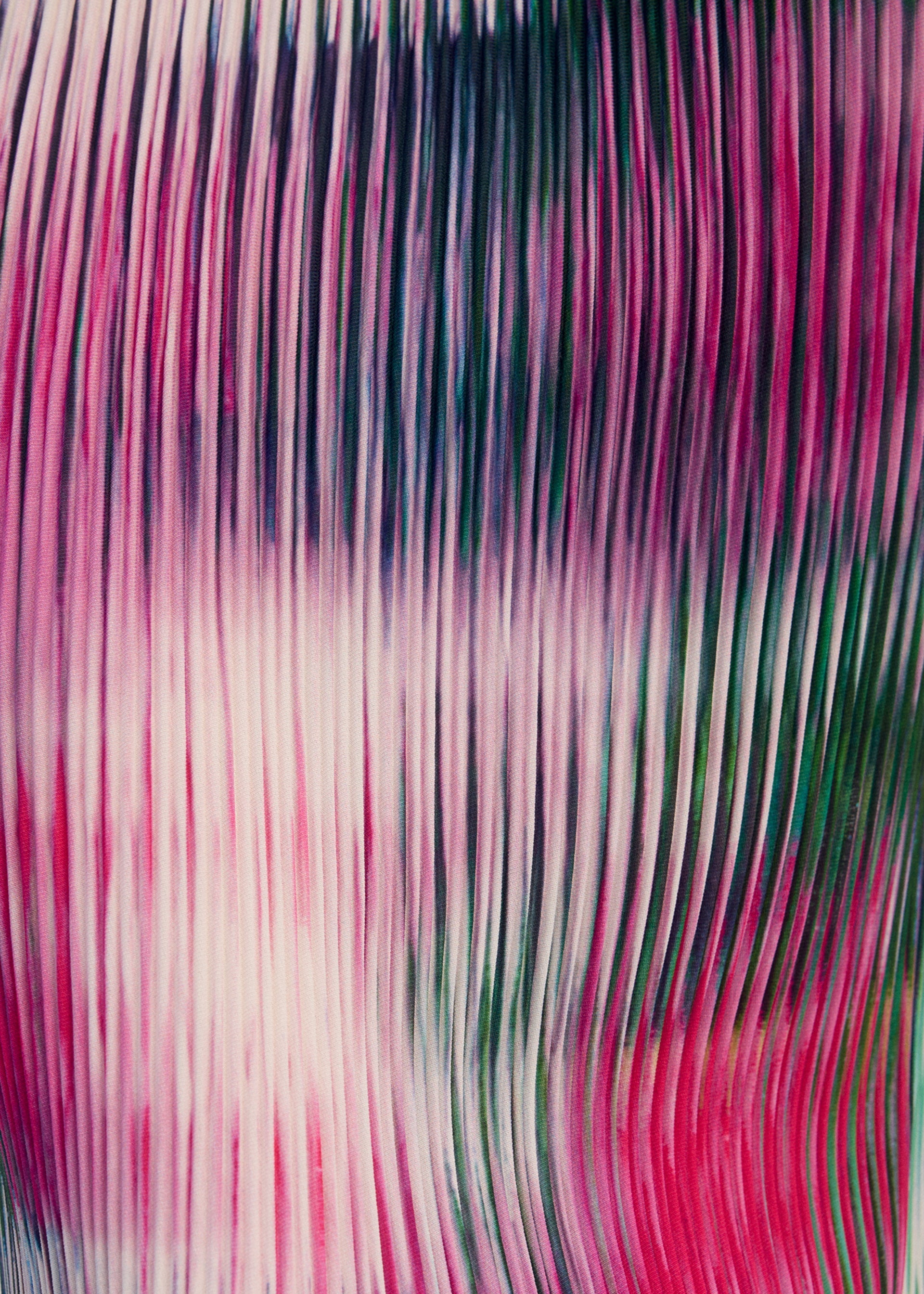 Zoomed view OBSCURE PLEATS by ISSEY MIYAKE features vertical, wavy lines in pink, red, green, and white, creating a blurred striped pattern that evokes the motion and texture of pleated polyester.