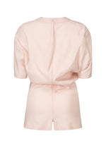 Back view of the GENERIC WEAR romper by ISSEY MIYAKE in light pink, featuring a high round neckline, visible center zipper, and a relaxed fit with playful design.