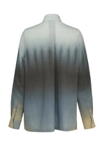 The back view of ISSEY MIYAKE's PLUMAGE shows a long-sleeve buttoned shirt featuring a gradient feather pattern that fades from light beige at the cuffs to dark gray, ending in light blue near the shoulders and upper back.