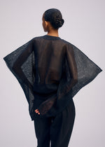 Facing away, a person with hair in a low bun wears the ISSEY MIYAKE CIALDA sheer mesh-textured black top with wide sleeves and black pants. One hand is behind their back against a plain, light background.