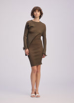 A person with short curly hair models ISSEY MIYAKE's ADVENTITIOUS: SLEEVES—a fitted, long-sleeve asymmetrical olive knit tunic dress—paired with white open-toe sandals against a light background, showcasing understated elegance and versatile style.