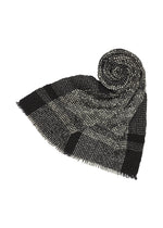 The BUMPY WOOL STOLE by ISSEY MIYAKE features a black and gray plaid pattern with fringed edges, partially rolled into a spiral on a white background to highlight its subtly bumpy texture. - BLACK-HUED （no.17）