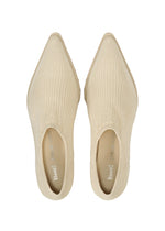 A pair of ANNA cream-colored, ribbed knit slip-on shoes by ISSEY MIYAKE, featuring pointed toes and a sock-like silhouette, viewed from above on a white background.