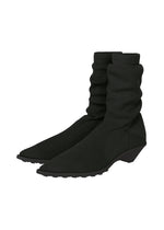 Black, ribbed, sock-like ankle boots from ISSEY MIYAKE's ANNA collection, featuring pointed toes, slouched shafts, and low angled block heels, shown against a white background. - BLACK （no.15）