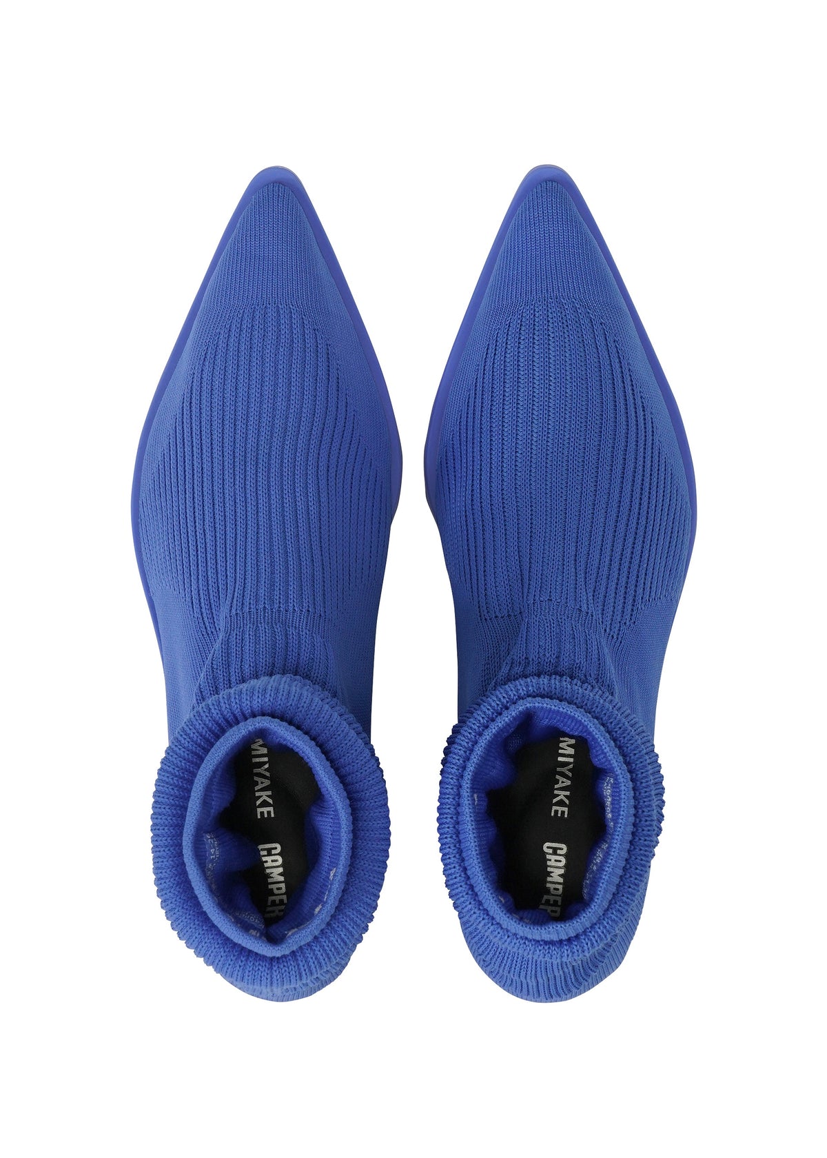 Top view of a pair of pointed-toe, ribbed, royal blue sock boots showcasing a sleek, sock-like shoe design with ISSEY MIYAKE and ANNA text visible on the black inner soles. view 6 of 11