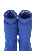 Two blue ribbed knit socks from ISSEY MIYAKE’s ANNA collection are positioned side by side, viewed from above. Reminiscent of stylish knitted footwear, the inside cuffs display partially visible white text. The background is plain white.