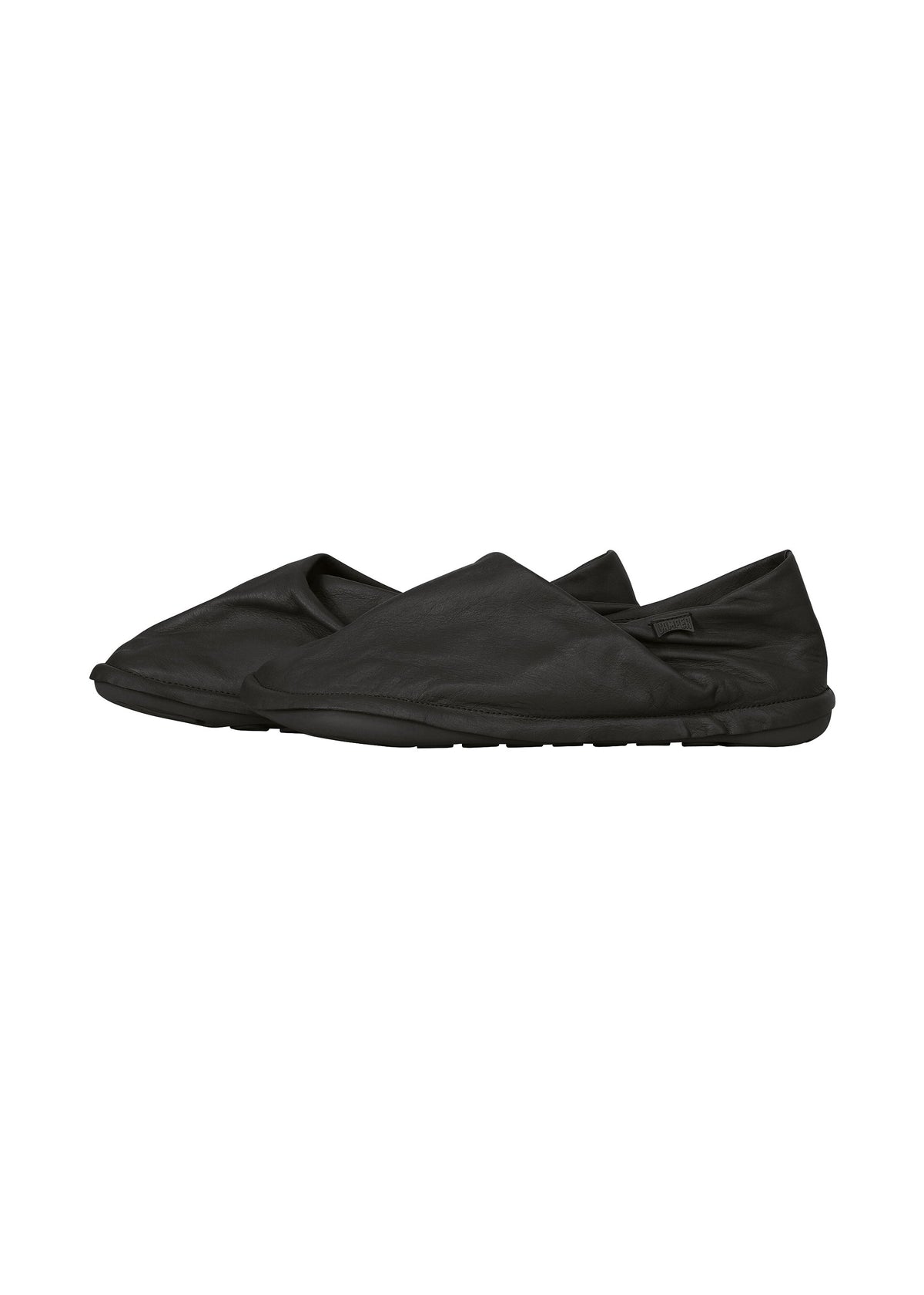 The ISSEY MIYAKE PEU FORM shoes are a pair of black slip-ons featuring a minimalist, soft design and flat rubber soles inspired by the Peu Form silhouette, shown on a white background. view 3 of 8