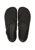 A pair of black PEU FORM slippers by ISSEY MIYAKE, crafted from soft leather with rounded toes, are shown from above against a white background. Their simple, unembellished design reflects the minimalistic style synonymous with the brand.