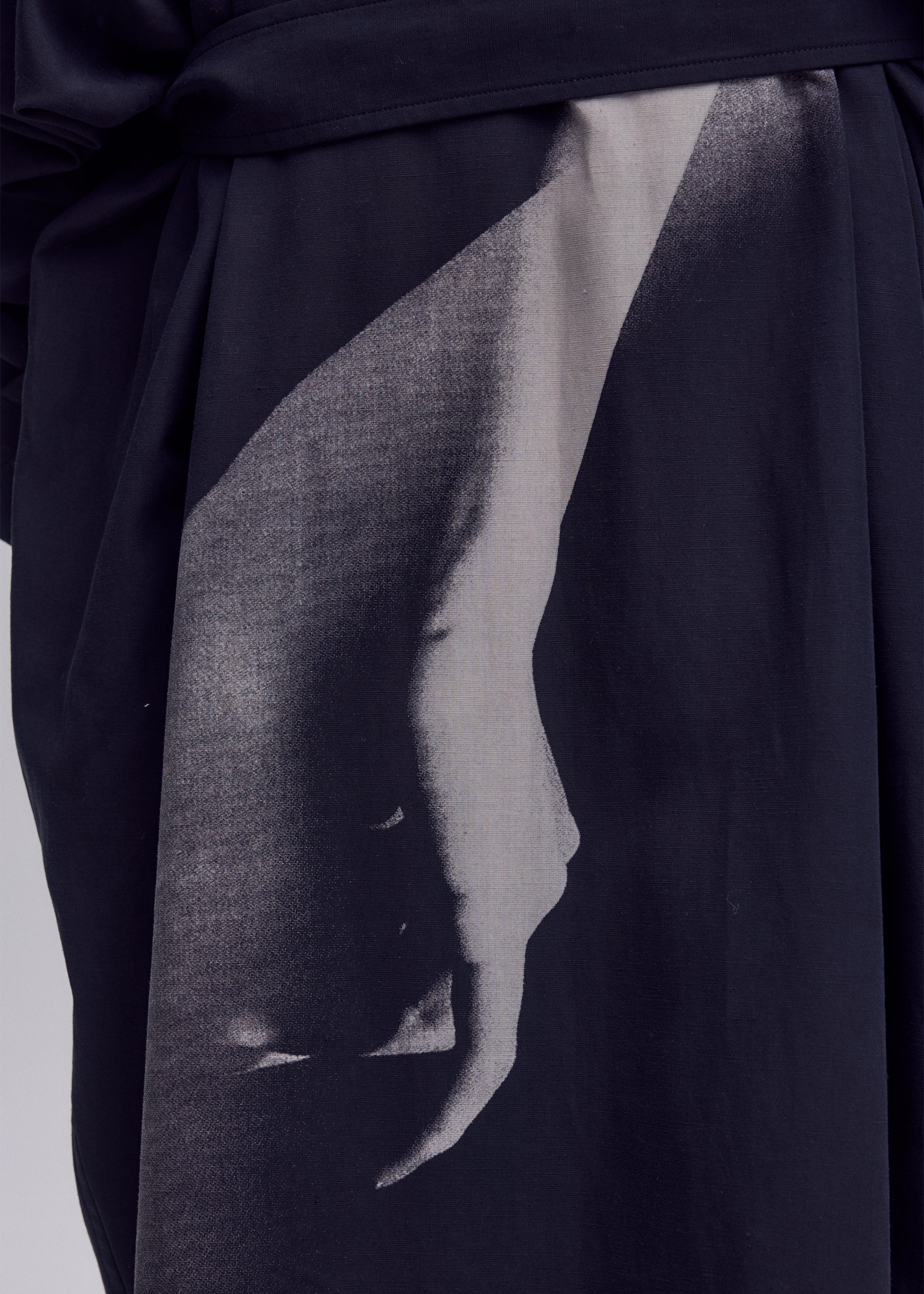 Zoomed view A close-up of black poplin fabric from ISSEY MIYAKE’s HANDS OF LOVER, featuring a silk-screen discharge printed grayscale image of a hand and forearm that creates dramatic shadow and contrast.