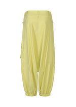 The ISSEY MIYAKE GRAINY PANTS are yellow baggy sarouel trousers made from stretch cotton, featuring an elasticated hem, belt loops, and side pockets, shown against a white background.