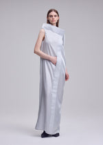 A person stands indoors wearing the ISSEY MIYAKE MERCURY, a sleeveless floor-length dress with an asymmetric collar and side seam pocket, set against a plain gray background.