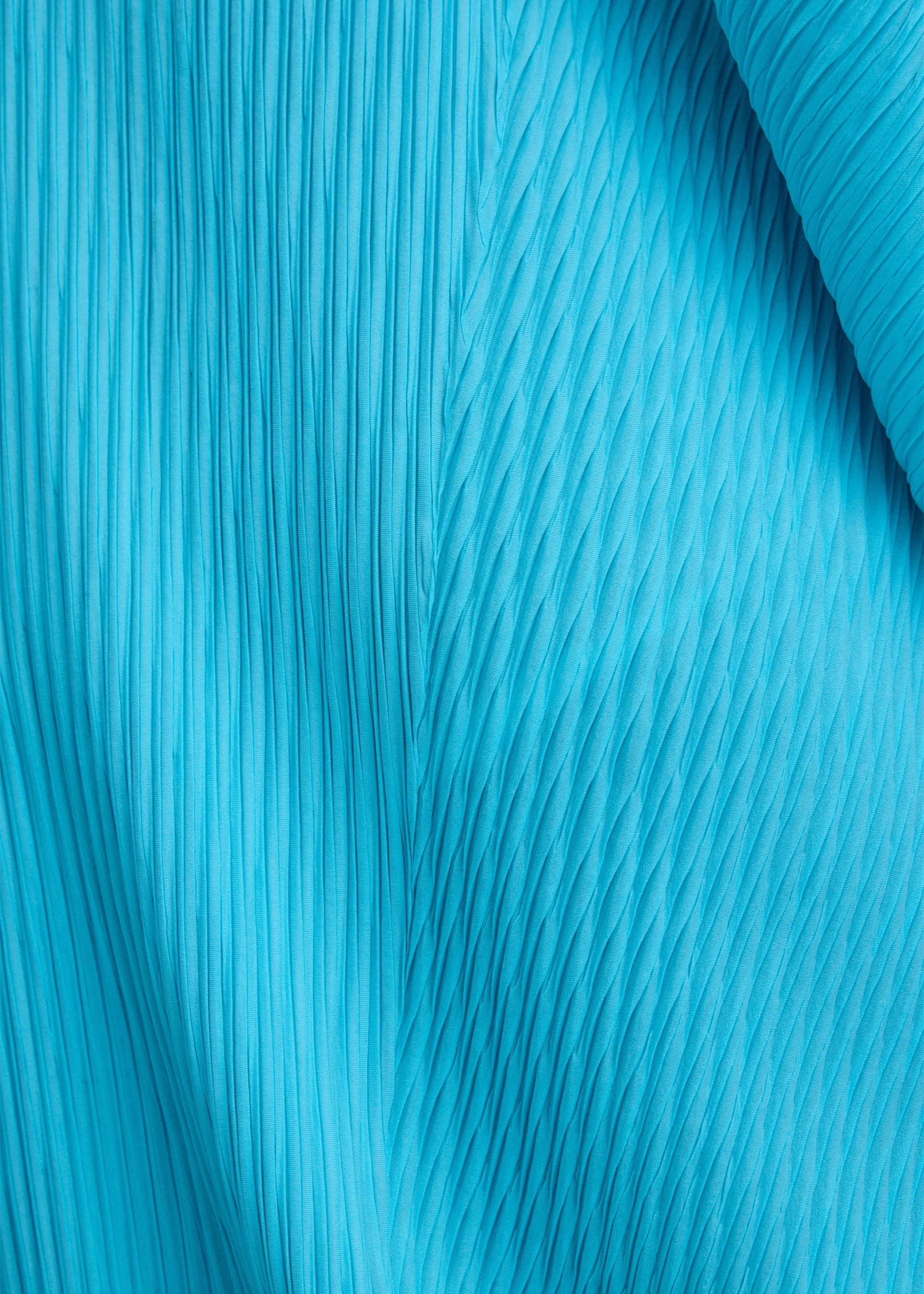Zoomed view Close-up of LEAF PLEATS by ISSEY MIYAKE, featuring bright blue fabric with double pleating and textured patterns that run vertically and diagonally, evoking a dynamic visual effect reminiscent of a leaf silhouette.