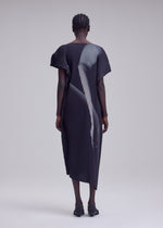 A person stands with their back to the camera, dressed in the HANDS OF LOVER PLEATS by ISSEY MIYAKE—a dark, short-sleeved dress made from polyester crepe de chine featuring original pleats. Its abstract design is vividly rendered using precise inkjet printing, set against a simple, light-colored background.