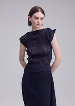 A woman with short brown hair wears the ZIGZAG PLEATS sleeveless top and matching skirt by ISSEY MIYAKE, featuring a subtle pleated texture. She stands against a plain light gray background, looking slightly to her left with a neutral expression.