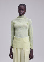 A person stands facing forward, dressed in the ISSEY MIYAKE ZIGZAG PLEATS set—a sheer, textured polyester long-sleeve top in light yellow with a subtle zigzag hem and matching wide-leg pants—against a plain light gray background.