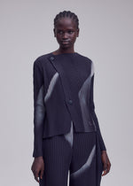A person with braided hair models the HANDS OF LOVER PLEATS set by ISSEY MIYAKE, featuring a pleated, long-sleeve top and matching pants made from dark polyester crepe de chine adorned with light abstract streaks in an original inkjet-printed pattern, standing against a plain light gray background.