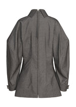 Back view of ISSEY MIYAKE’s REFLECTION—a gray, long-sleeved, collared jacket with a visible center zipper and wide, slightly puffed sleeves crafted from reflector fabric. This tailored piece features wrist straps with buttons and subtle reflective detailing that blend utilitarian style with innovative design.