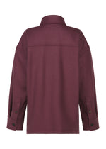 The back view of the MANNER long-sleeve maroon jacket by ISSEY MIYAKE, made from leftover fabric, features a collar, visible seam details, and buttoned cuffs.