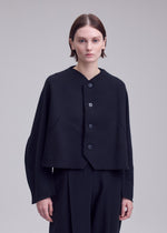 A person with short brown hair wears the ISSEY MIYAKE CAMPAGNE black buttoned jacket, crafted from innovative A-POC material, along with matching black pants, standing against a plain light gray background.