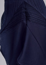 Close-up of the SHADE AND SHADED_NY skirt by ISSEY MIYAKE in dark blue, featuring pleated and smooth geometric sections. The slightly shiny fabric adds depth, highlighting the garment's unique architectural design.