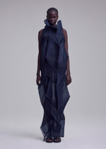 A model wears the SHADE AND SHADED_NY dress by ISSEY MIYAKE—a sleeveless, high-neck, dark blue geometric ankle-length dress crafted from sheer, layered fabric with bold angular patterns and a sculptural silhouette.
