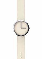 The ISSEY MIYAKE WATCH TWELVE, designed by Naoto Fukasawa, features a cream strap and face, a silver octagonal bezel, simple black hands, and no numbers. ISSEY MIYAKE is at the 3 o'clock position on the minimalist dial.