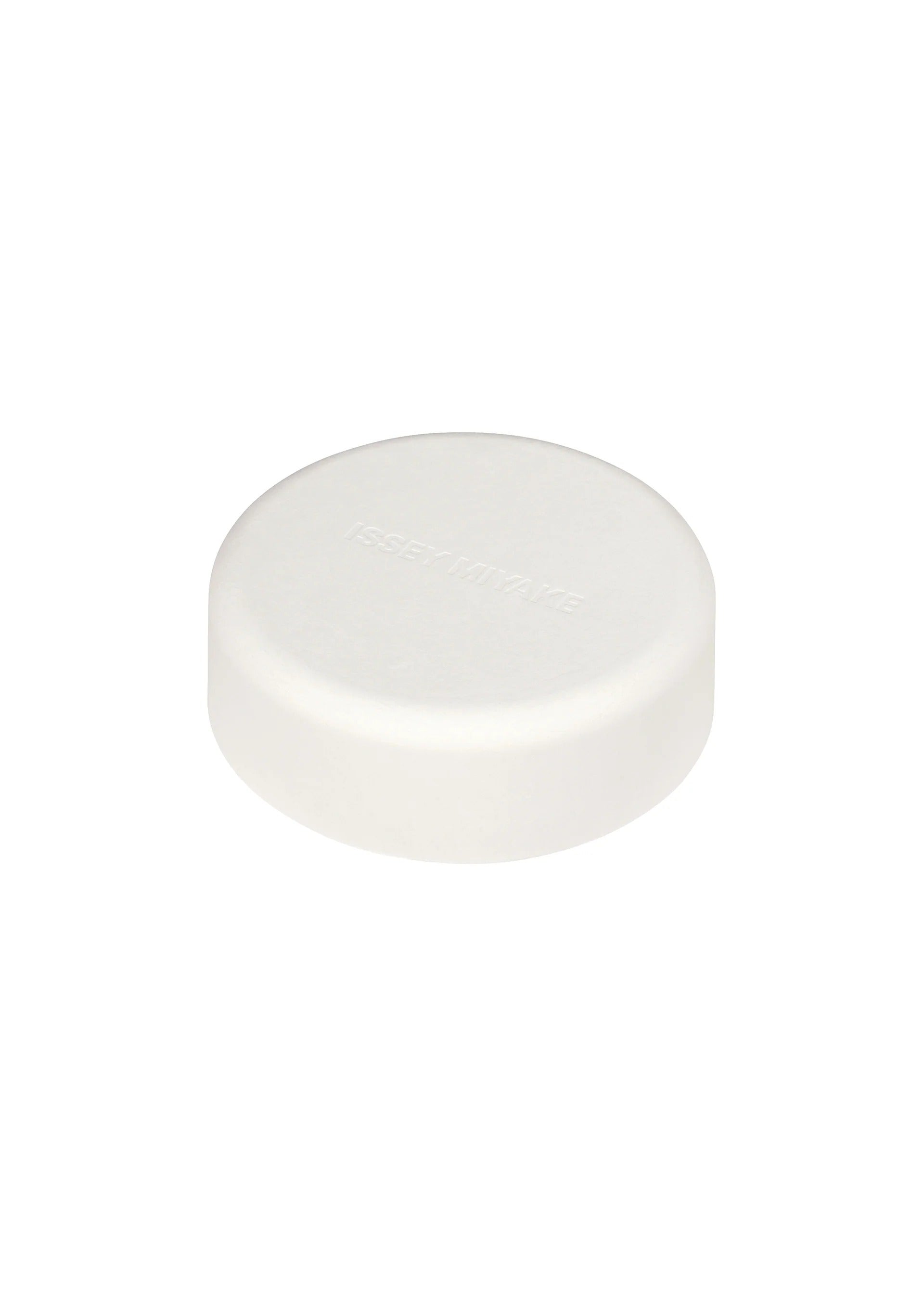 Zoomed view A single round, white tablet with a smooth surface and subtle, indented text rests on a plain white background—its minimalist aesthetic reflecting the refined design sensibility of Tokujin Yoshioka, as seen in the O watch for ISSEY MIYAKE WATCH.