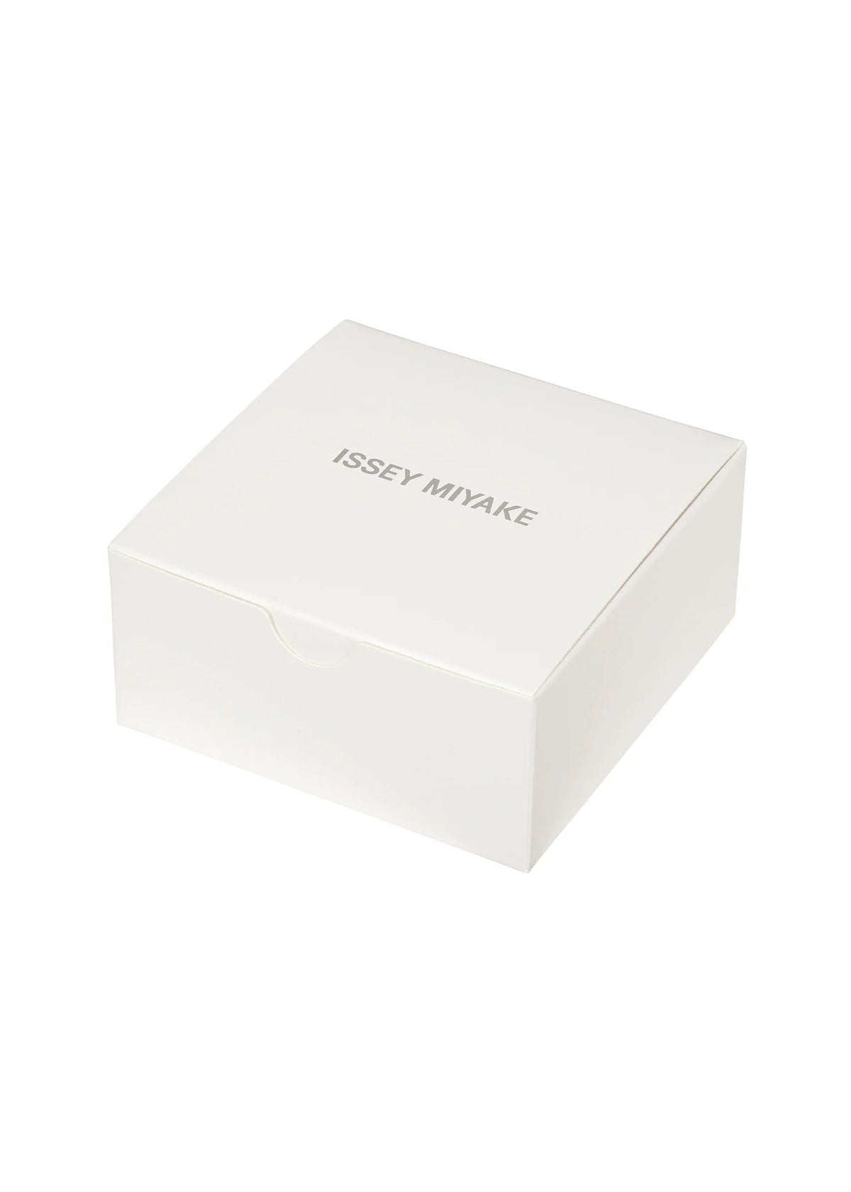 A plain white square box with ISSEY MIYAKE WATCH printed in gray uppercase letters on the lid. Designed with a simple, minimalist aesthetic and set against a white background, the box perfectly embodies the iconic style of Tokujin Yoshioka—the designer behind “O” by ISSEY MIYAKE WATCH, as well as the brand’s renowned lightweight bangle watch and transparent watch collections. view 5 of 6